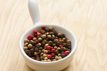 Mixed pepper in ceramic bowl  on wooden background