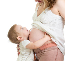 Little boy hugging pregnant mother's belly and looking up