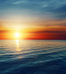 Obraz na płótnie Canvas czerwony zachód słońca nad ciemną wodą
