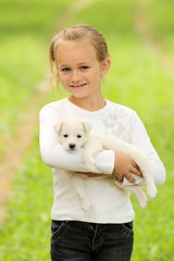 Little girl smiling and holding a white puppy