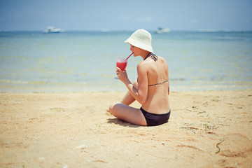 Fototapeta na wymiar relaks kobieta siedzi na piasku z koktajl