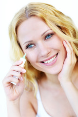 Smiling woman applying concealer in front of mirror