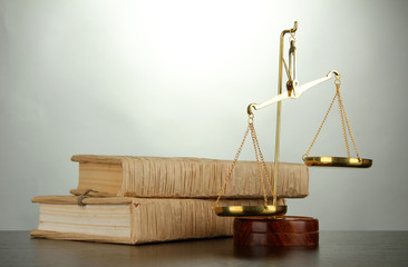 Gold scales of justice and books on grey background