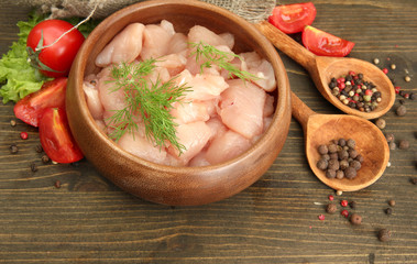 raw chicken meat in bowl, on wooden background
