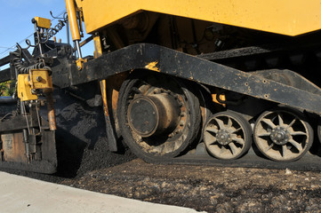Fototapeta na wymiar Wheels of an asphalt paving machine on new road
