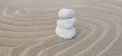galets blancs zen en équilibre dans le sable
