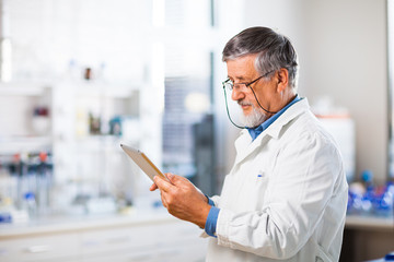 Senior doctor/scientist using his tablet computer at work