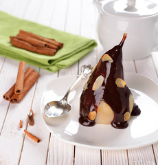 Pear with chocolate sauce on a white table