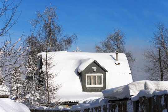 snow-covered roof of village house and bright blue sky