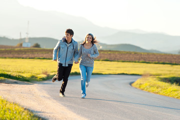 Obraz premium Teen couple running in countryside.