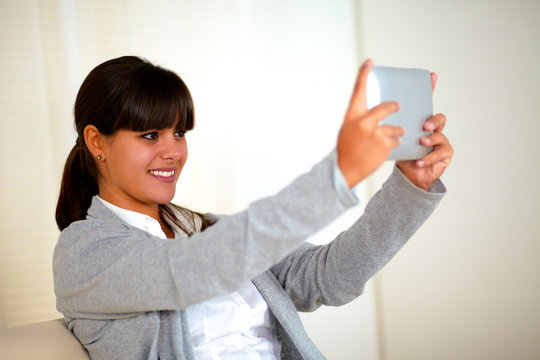 Smiling young woman taking picture with tablet pc