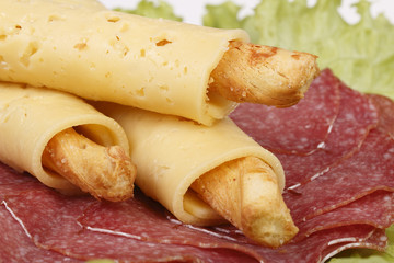 Salty cheese sticks with salami on lettuce