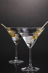 Martini glasses and olives on grey background