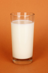 Glass of fresh new milk on brown background