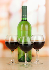 Red wine in glass and bottle on room background