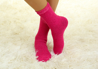 Female legs in colorful socks on  white carpet background