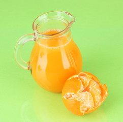 Full jug of tangerine juice, on wooden color  background