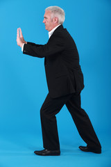A mature businessman miming.