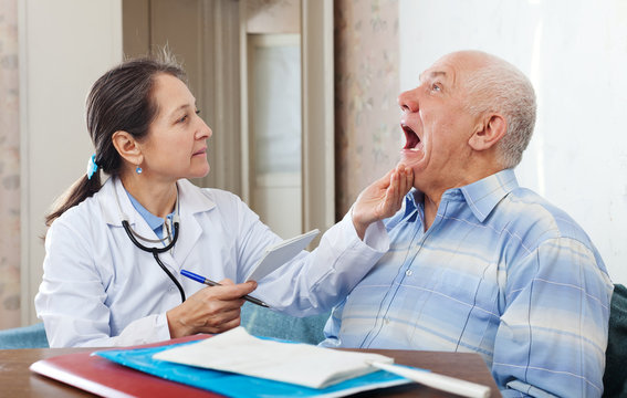mature doctor looks the mouth of  patient