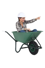 Female tradesperson sitting in a wheelbarrow