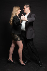 Dancing couple in love. Studio shot against black.
