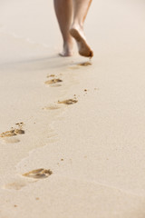 Frau hinterlässt Fußspuren am Sandstrand