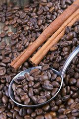 Coffee beans and cinnamon on wooden table with a spoon.