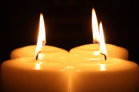 Four candles alight in a darkness