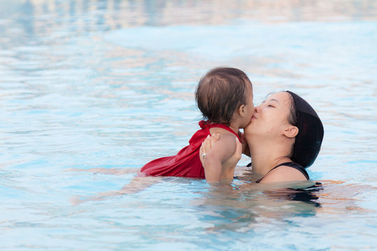 Mother kissing her daughter in pool