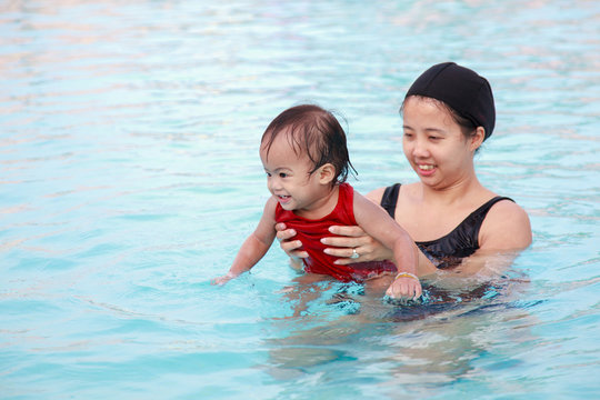 Mother play with daughter in pool