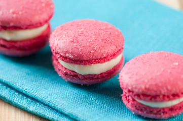 Row of pink macaroons on a turquoise serviette, studio shot