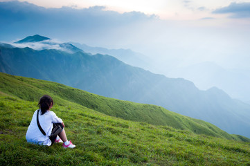 Fototapeta na wymiar Mountain Girl siedzi na trawniku widzenia