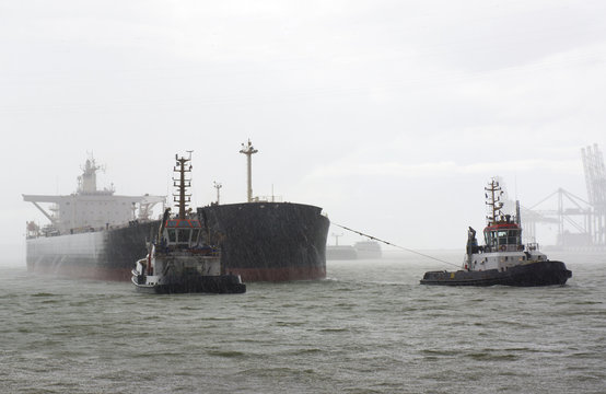 Vessel and tugboats in heavy rain