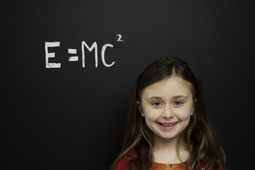 Smart young girl stood infront of a blackboard