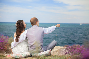 bride and groom sitting back watching the sea