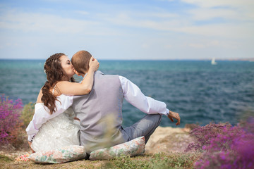 bride and groom sitting back watching the sea