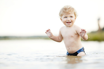 little funny boy playing in lake