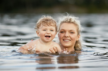 beautiful young mother with son in water