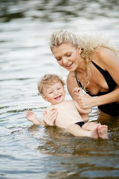 beautiful young mother with son in water