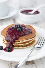 stack of pancakes with black currant jam on a plate closeup
