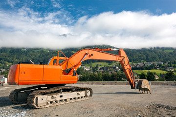 Excavator at construction site on austrian alps background