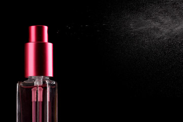 women's perfume in bottle and spraying, on black background