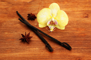 Vanilla pods and anise with flower, on brown wooden background