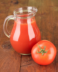 Full jug of tomato juice, on wooden background