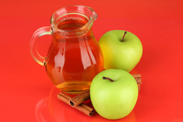 Full jug of apple juice and apple on color background