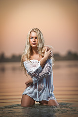 Naklejka premium Sexy blonde woman play in white lingerie in a river water