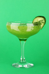 Green vegetable juice in coctail glass on green background