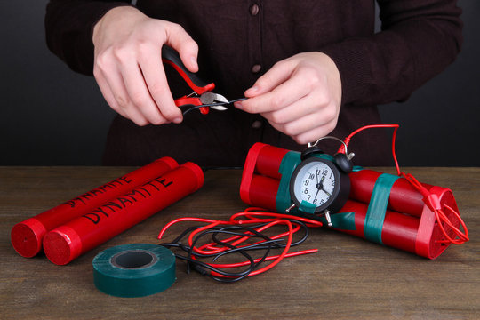 Human makes timebomb on wooden table on black background