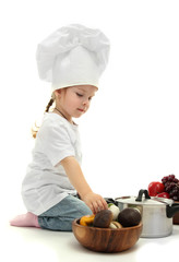 little girl doctor in chef's hat with pan and vegetables,