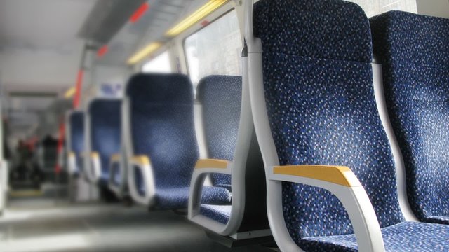 Dark blue chairs with yellow armrests stand in carriage of train